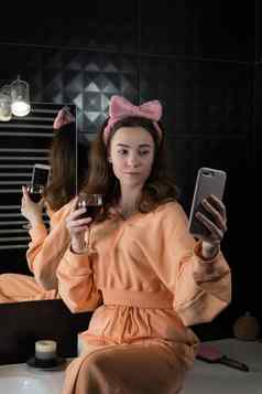 有吸引力的年轻的女人浴室沟通智能手机喝酒放松休闲概念