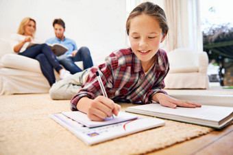 家庭作业=放松时间拍摄女孩说谎生活房间地板上家庭作业父母背景