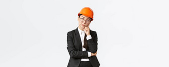 深思熟虑的有创意的女亚洲首席架构师建设工程师思考穿安全头盔西装思考选择建筑站白色背景