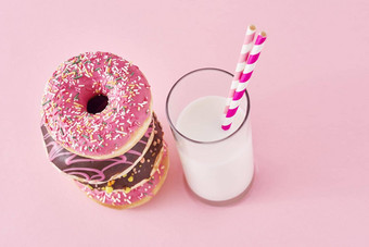 堆栈色彩斑斓的甜甜圈装饰玻璃牛奶粉红色的背景
