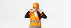 亚洲女公司经理感觉不舒服首席工程师关闭耳朵扮鬼脸烦人的噪音检查工作建设区可怕的声音维修穿安全头盔