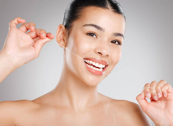 清洁牙齿快乐牙齿工作室拍摄有吸引力的年轻的女人用牙线清洁牙齿牙齿灰色背景