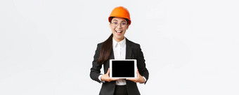 兴奋惊讶微笑亚洲女建设工程师架构师安全头盔业务西装显示数字平板电脑屏幕惊讶表达式站白色背景