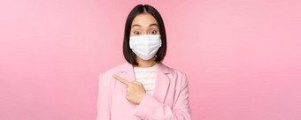 肖像亚洲女商人医疗脸面具西装指出手指左显示广告公司横幅工作室粉红色的背景