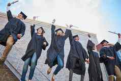 毕业庆祝活动低角拍摄快乐集团学生跳庆祝活动毕业一天