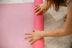 年轻的女人卷粉红色的健身瑜伽席锻炼锻炼首页生活房间瑜伽工作室健康的习惯适合重量损失概念特写镜头照片