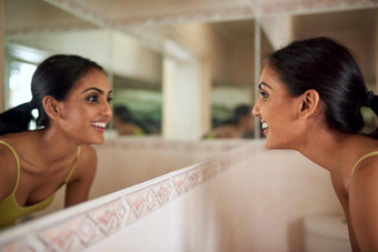 保持皮肤更健康的重新焕发了生机裁剪拍摄年轻的女人脸浴室镜子