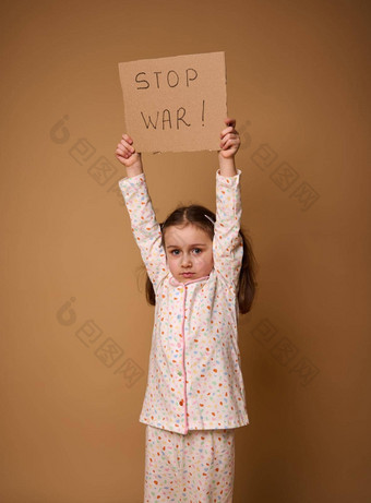 可爱的心烦意乱孩子伤心欧洲女孩睡衣持有停止战争社会消息纸板海报站米色背景复制空间