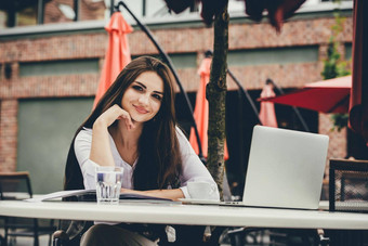 年轻的自由职业者女人移动PC电脑坐着咖啡馆表格微笑女人工作在线研究学习笔记本