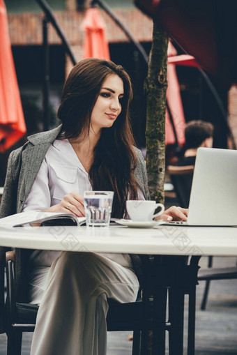 年轻的自由职业者女人移动PC电脑坐着咖啡馆表格微笑女人工作在线研究<strong>学习笔记</strong>本