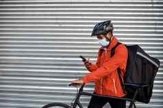 检查应用程序交付位置拍摄戴面具的男人。手机自行车交付