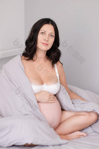 期待妈妈。巨大的肚子甜蜜的怀孕时间快乐女人怀孕了肚子光卧室首页舒适的室内