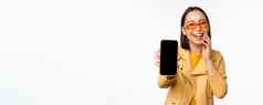 热情的亚洲女模型显示智能手机应用程序接口在线商店网站移动电话屏幕站白色背景