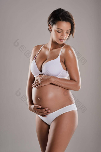 一天工作室拍摄美丽的年轻的怀孕了女人摆姿势内衣灰色的背景