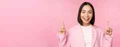 微笑朝鲜文女商人指出手指显示广告横幅标志前站西装粉红色的背景