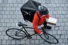 信任交付货物时间一块拍摄戴面具的男人。自行车交付