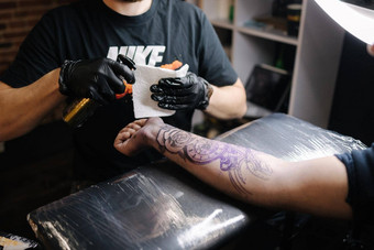 关闭年轻的专业纹身主介绍了黑色的墨水皮肤针纹身机纹身手