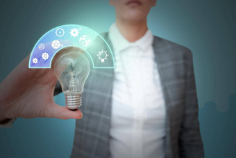 夫人西装持有光灯泡代表创新思考象征着未来主义的技术女人展示电灯显示成功有创意的思考
