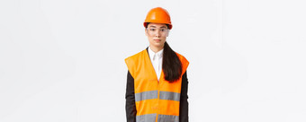 严肃的表情专业女亚洲建设工程师架构师建筑区域穿统一的安全头盔业务西装站白色背景检查企业