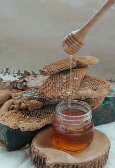 美味的蜂蜜滴木蜂蜜七星坚持玻璃Jar新鲜的蜂窝背景