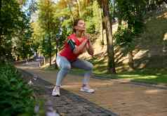美丽的自信女运动员深下蹲享受户外锻炼温暖的阳光明媚的夏天一天体育运动健身功能身体重量培训