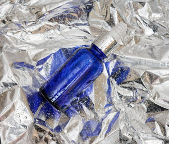 蓝色的玻璃瓶吸管背景皱巴巴的灰色的箔药店概念胶原蛋白皮肤模型护肤品化妆品产品