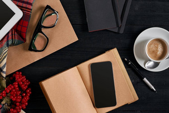 视图聪明的电话笔记本杯拿铁咖啡黑色的木背景