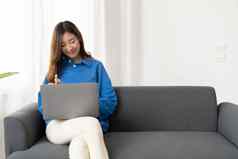 年轻的亚洲业务女人工作首页移动PC电脑在线互联网沙发自由女孩笔记本沙发上安慰正常的生活方式概念Copyspace