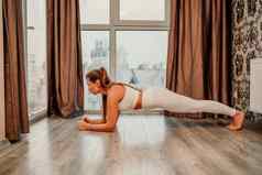 年轻的有吸引力的运动女人白色运动服装推联合包裹俯卧撑健身房席首页练习瑜伽板材构成锻炼在室内健康的活跃的生活方式概念