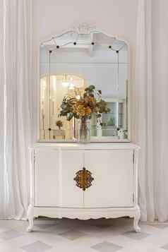 恢复家具经典明亮的室内白色墙窗帘古董镜子花花束木橱柜