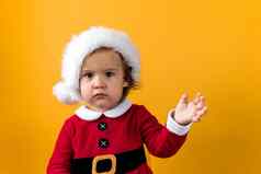 伤心portraite可爱的快乐快乐的胖乎乎的婴儿女孩圣诞老人他挥舞着手黄色的背景孩子玩圣诞节场景庆祝生日孩子有趣的花一年时间复制空间