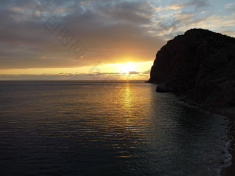 空中全景视图美丽的日落平静Azure海火山岩石海岸太阳眩光小波水表面地平线人永无止境的美自然