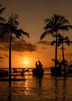 夫妇但女人看日落热带海滩毛里求斯棕榈树游泳池热带日落海滩毛里求斯