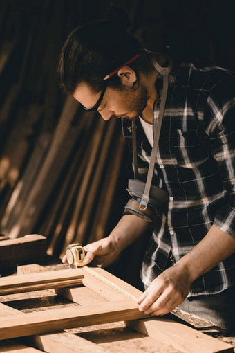 卡彭特男人。参加使杰作木制品手工制作的家具细测量木车间垂直拍摄