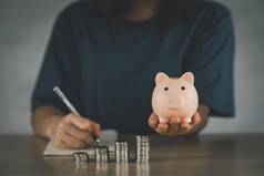 女人持有粉红色的小猪银行一步日益增长的业务利润储蓄小猪银行储蓄钱未来计划退休基金概念