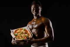 运动英俊的黑色的男人。作品披萨交付保持首页吃披萨美味的食物非洲男人。微笑显示披萨纸板盒子