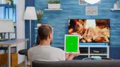 男人。坐着沙发持有垂直数字平板电脑绿色屏幕看在线社会媒体内容