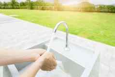 女人洗手利用水水龙头白色水槽洗手利用水户外水槽草场个人卫生防止冠状病毒科维德健康的生活方式