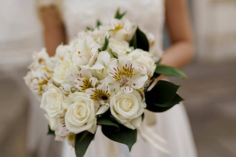 婚礼花束特写镜头白色玫瑰绿色叶子新娘衣服持有花束广告婚礼机构