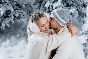 冬天爱故事夏娃一年庆祝活动夫妇拥抱圣诞节树冬天假期爱故事年轻的夫妇穿白色套头毛衣快乐男人。女人爱