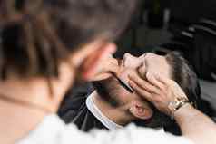 直剃须刀减少男人胡子理发店理发师男人。使发型英俊的男人。