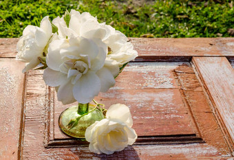 美丽的花束玫瑰滴绿色玻璃花瓶木表格