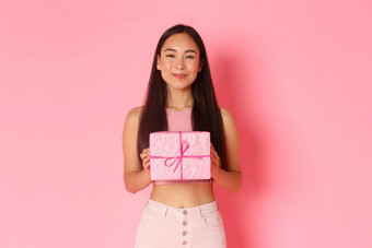 假期庆祝活动生活方式概念特写镜头很高兴快乐的亚洲女孩收到可爱的包装礼物微笑满意喜欢接收礼物站粉红色的背景
