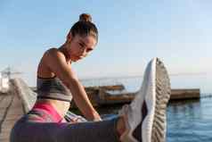 特写镜头有吸引力的女运动员持有腿handrope伸展运动海边散步女跑步者准备活动早....慢跑培训