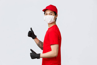 交付服务交付的家伙红色的帽t恤物流公司员工显示竖起大拇指站配置文件转相机保护医疗面具手套推荐快递服务