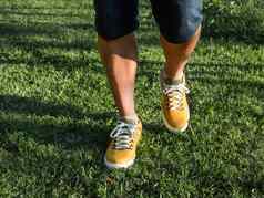 男人。明亮的黄色的运动鞋站绿色草草坪上公园现代时髦的鞋子城市时尚