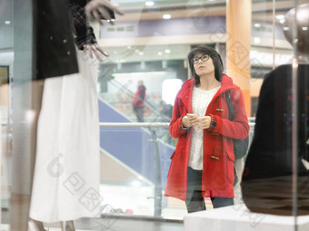 女人凝视着假人服装商店休闲装挂模特视图透明的商店窗口购物购物中心基本衣服日常穿现代城市时尚