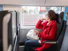 微笑女人红色的露营装备外套智能手机坐在窗口郊区火车旅行土地车辆