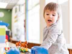 蹒跚学步的戏剧色彩斑斓的玩具块男孩凝视着数字玩具构造函数室内幼儿园托儿所在室内休闲活动孩子们
