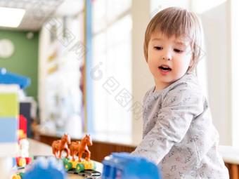 蹒跚学步的戏剧色彩斑斓的玩具块男孩凝视着数字玩具构造函数室内幼儿园托儿所在室内休闲活动孩子们